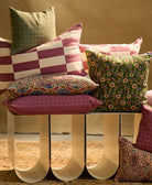 pine green cross stitch small pillow on stack of berry pillows on a bench