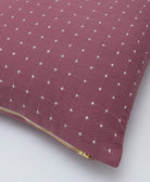 purple embroidered pillow with white cross-stitching