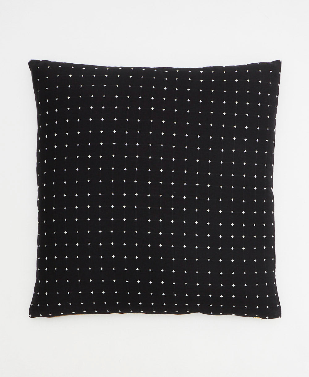 black throw pillow with white embroidery in a tiny cross-stitch pattern