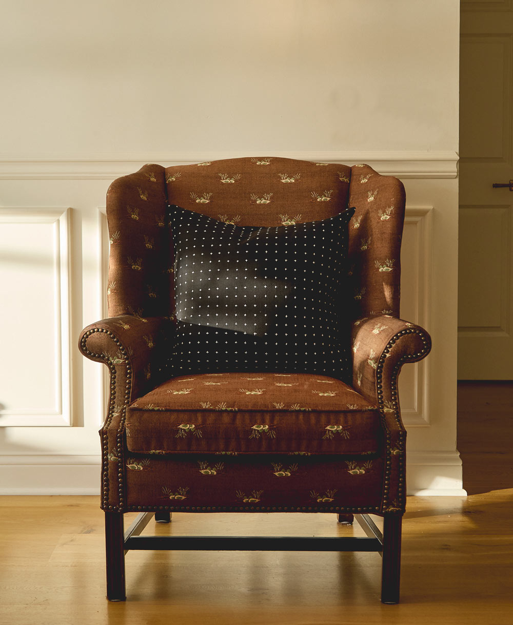 Decorative armchair with modern black throw pillow with tiny cross-stitching