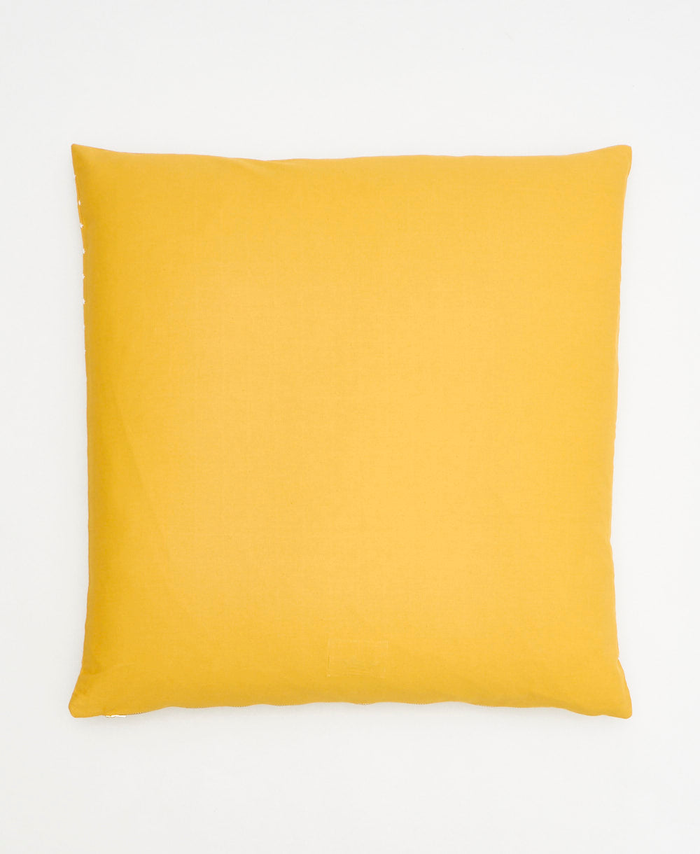 back of mustard yellow throw pillow with cross-stitch pattern on front and solid back