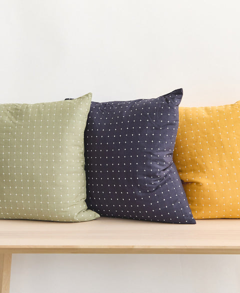 sage green, navy blue, and mustard yellow cross-stitch throw pillows sitting on light wooden entryway bench