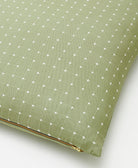 sage green throw pillow with cross-stitching and gold tone zipper closure with removable insert