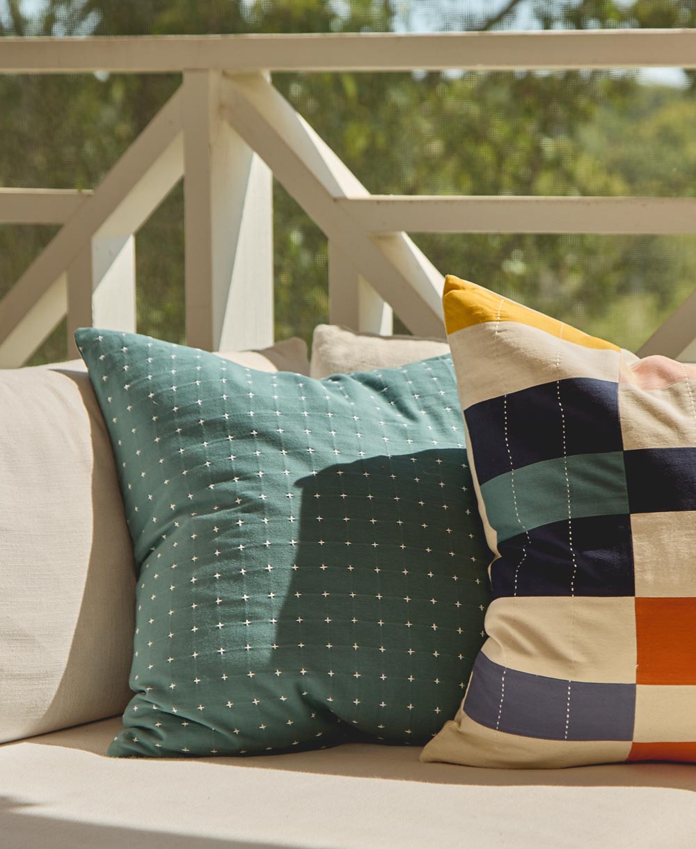 Decorative pillows on a couch with a blurred outdoor background