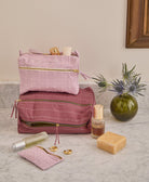 purple and lilac toiletry bags stacked on top of one another on gray countertop in bathroom