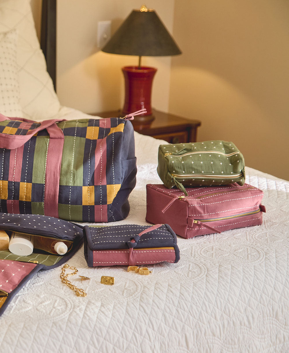 green and purple toiletry bags sitting on white bedspread