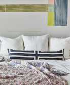 embroidered white euro shams on all white bed with pastel wall mural behind bed and neutral kantha quilt