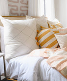 diamond stitch euro sham on all white bedding accented with pink and yellow throw pillows