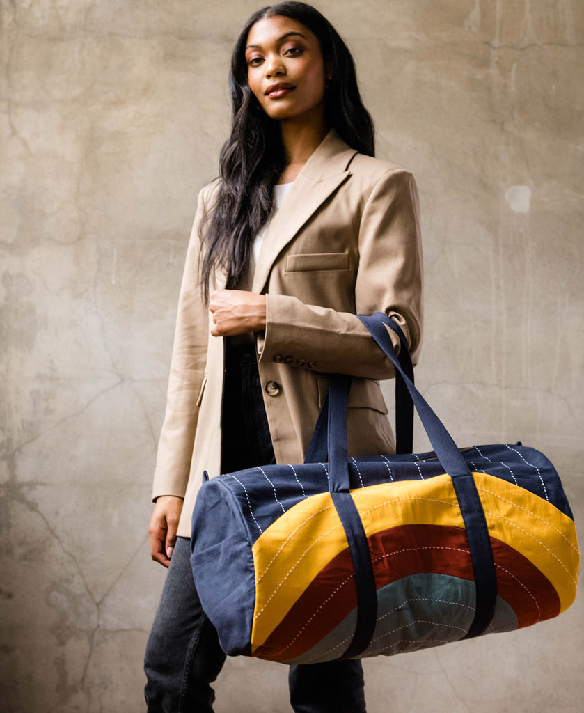 Bright colored weekender bag with curve design and white traditional stitching 