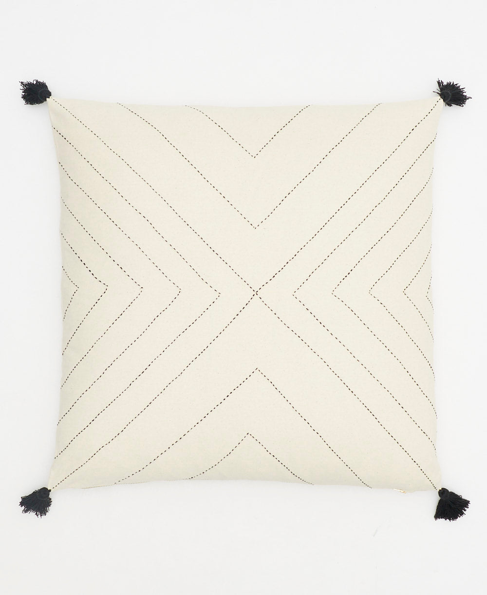 geometric stitch throw pillow with black embroidery and tassels