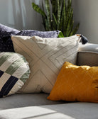 mismatched organic cotton throw pillows in mustard yellow, white, and navy blue on modern gray sofa corner