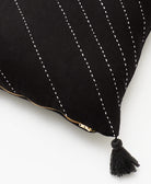 black tassel detail on square throw pillow with white hand-stitched embroidery