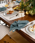 spruce green cotton table napkins and white embroidered placemats on wooden table set for brunch