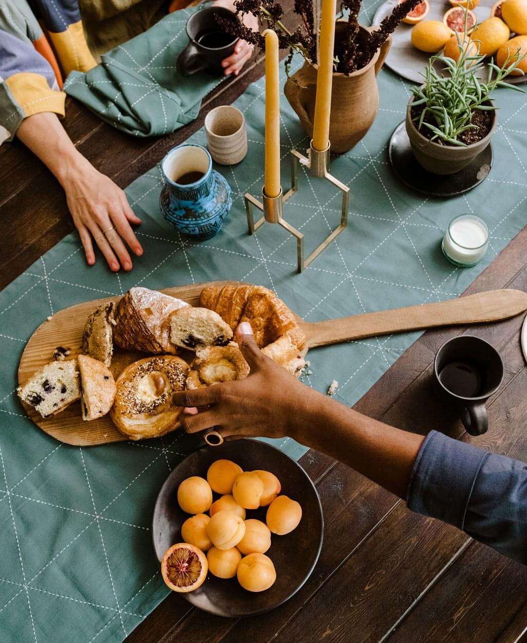 spruce green cotton table runner with bold geometric embroidery pattern with wooden serving platter on top with handmade bakery items