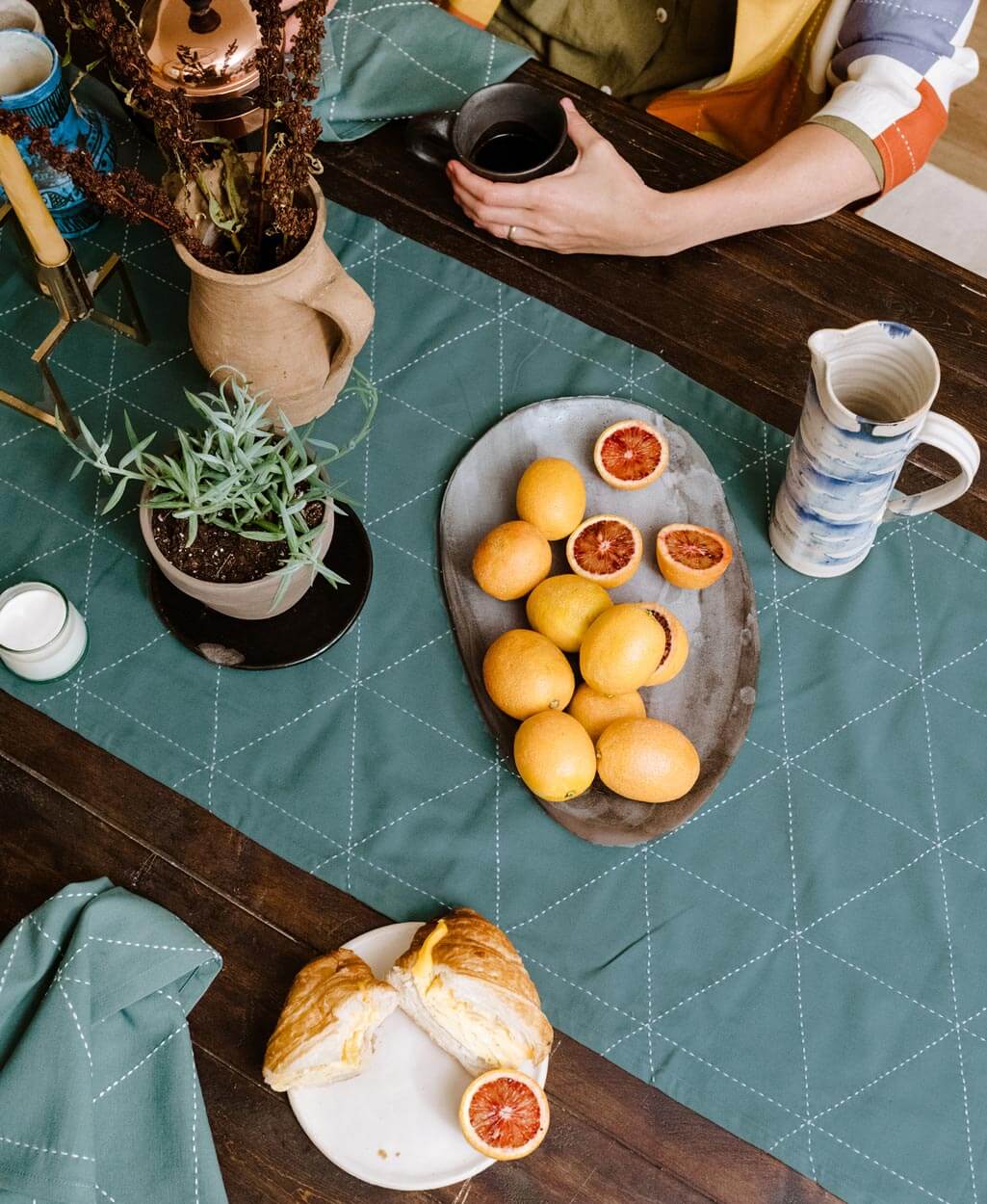 spruce green embroidered table runner with white stitching in a triangle pattern on dark vintage  wooden dining table