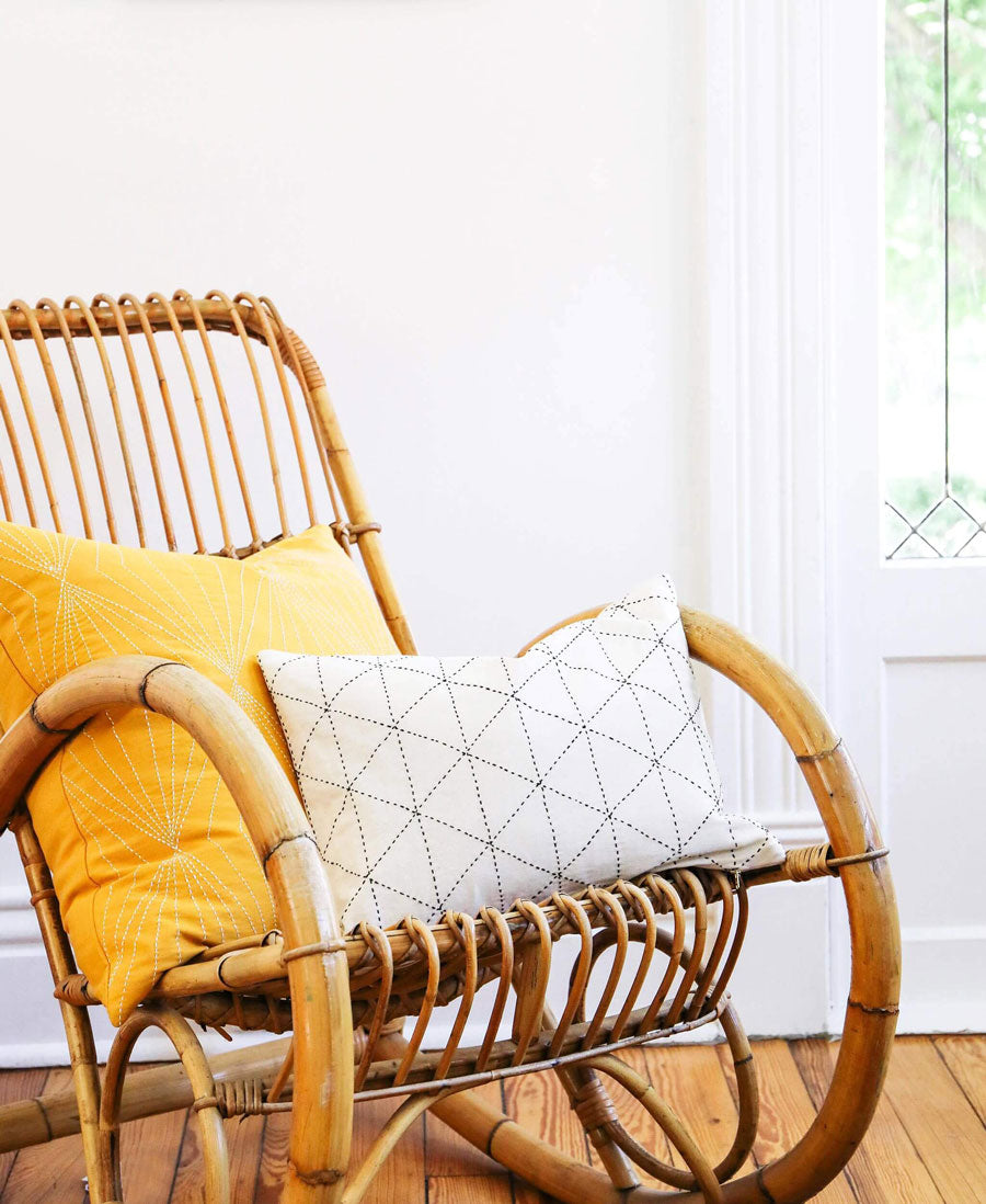 ethically made small white pillow in vintage rattan rocking chair near window