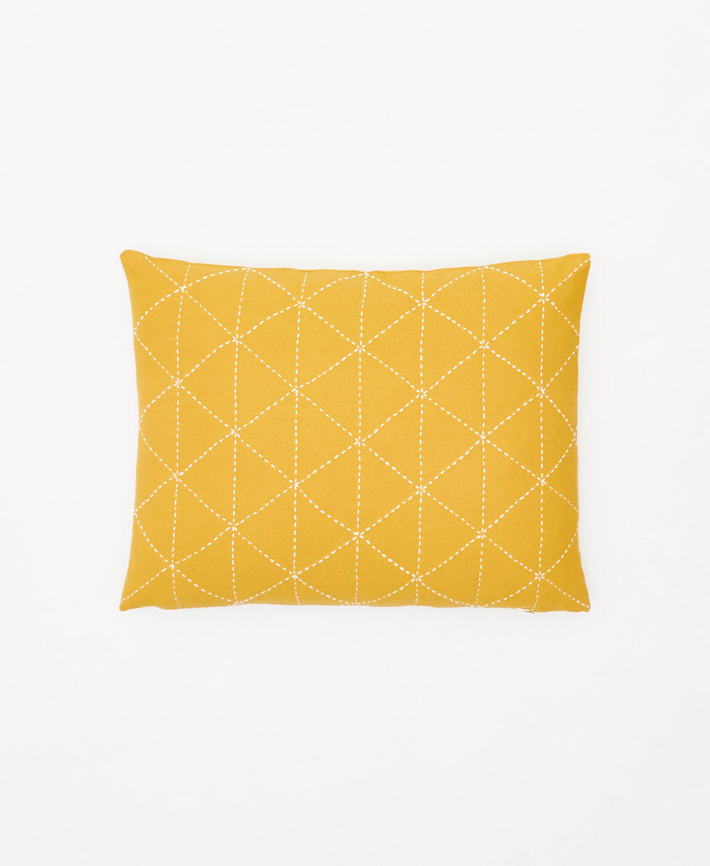 mustard yellow small pillow with white embroidery forming a geometric triangle pattern