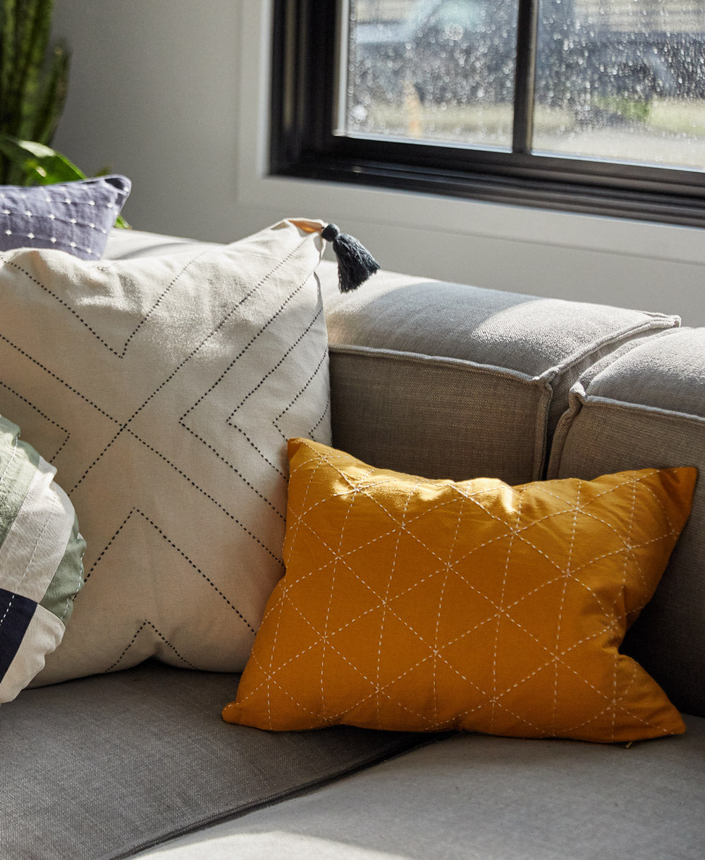 small lumbar pillow in mustard yellow on grey modular sofa with organic cotton white pillow next to it