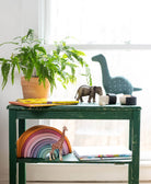 vintage green nightstand with potted plant, brass elephant and handmade cotton stuffed dinosaur in kids room