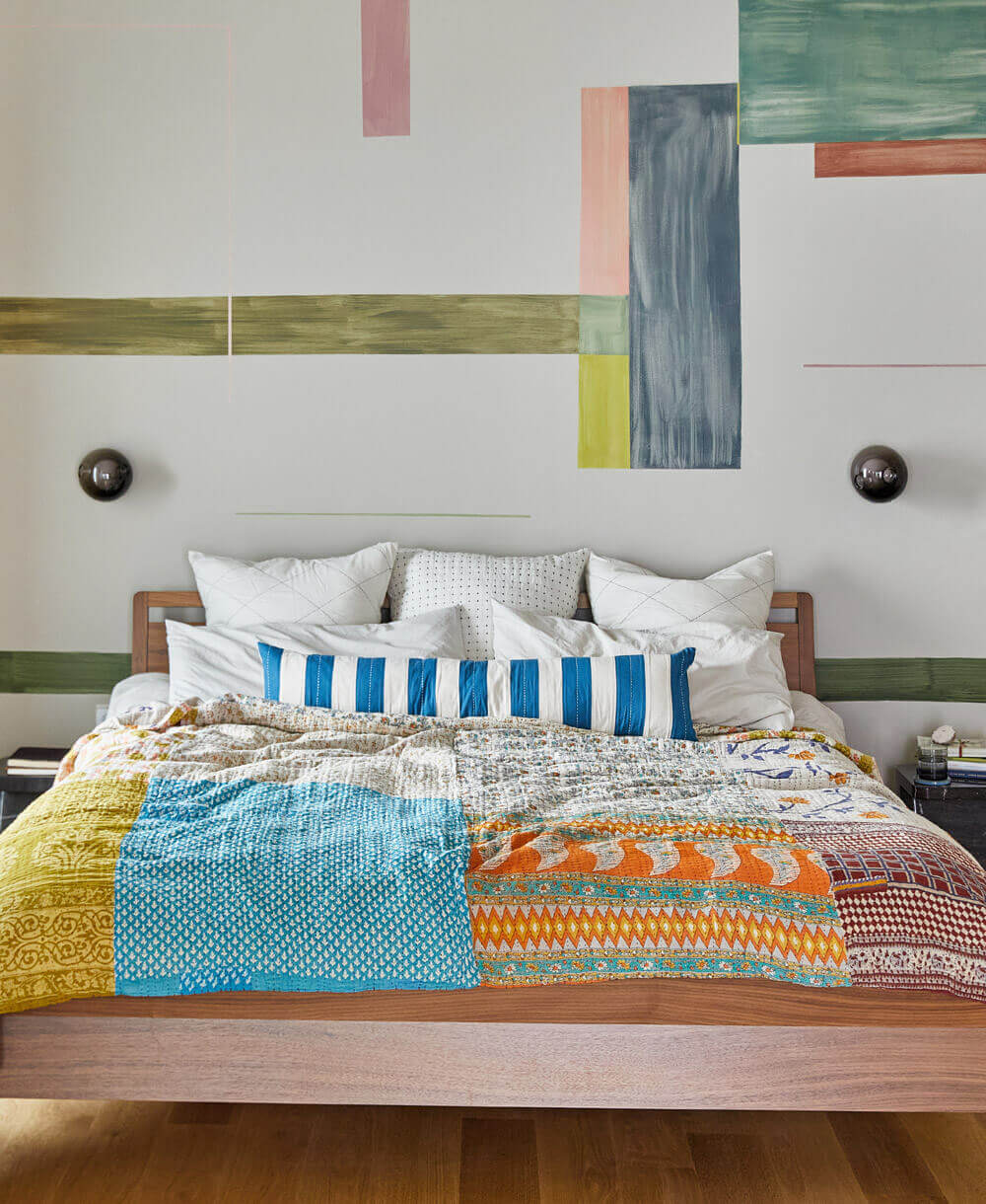 mixed pattern kantha quilt in shades of blue, green and orange on queen bed