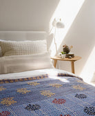 blue kantha quilt with floral print on queen size bed in all white bed linens by Anchal