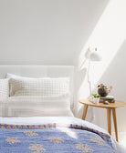 one-of-a-kind cornflower blue kantha quilt in queen size on all white bed with white wall sconce