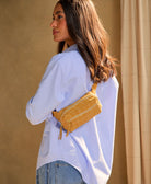 woman wearing ochre crossbody belt bag and a blue shirt