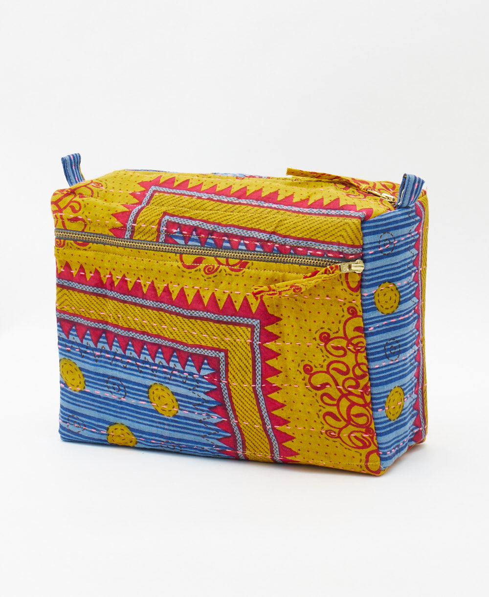 large toiletry bag featuring a yellow, red, and blue abstract print and pink traditional kantha hand stitching  