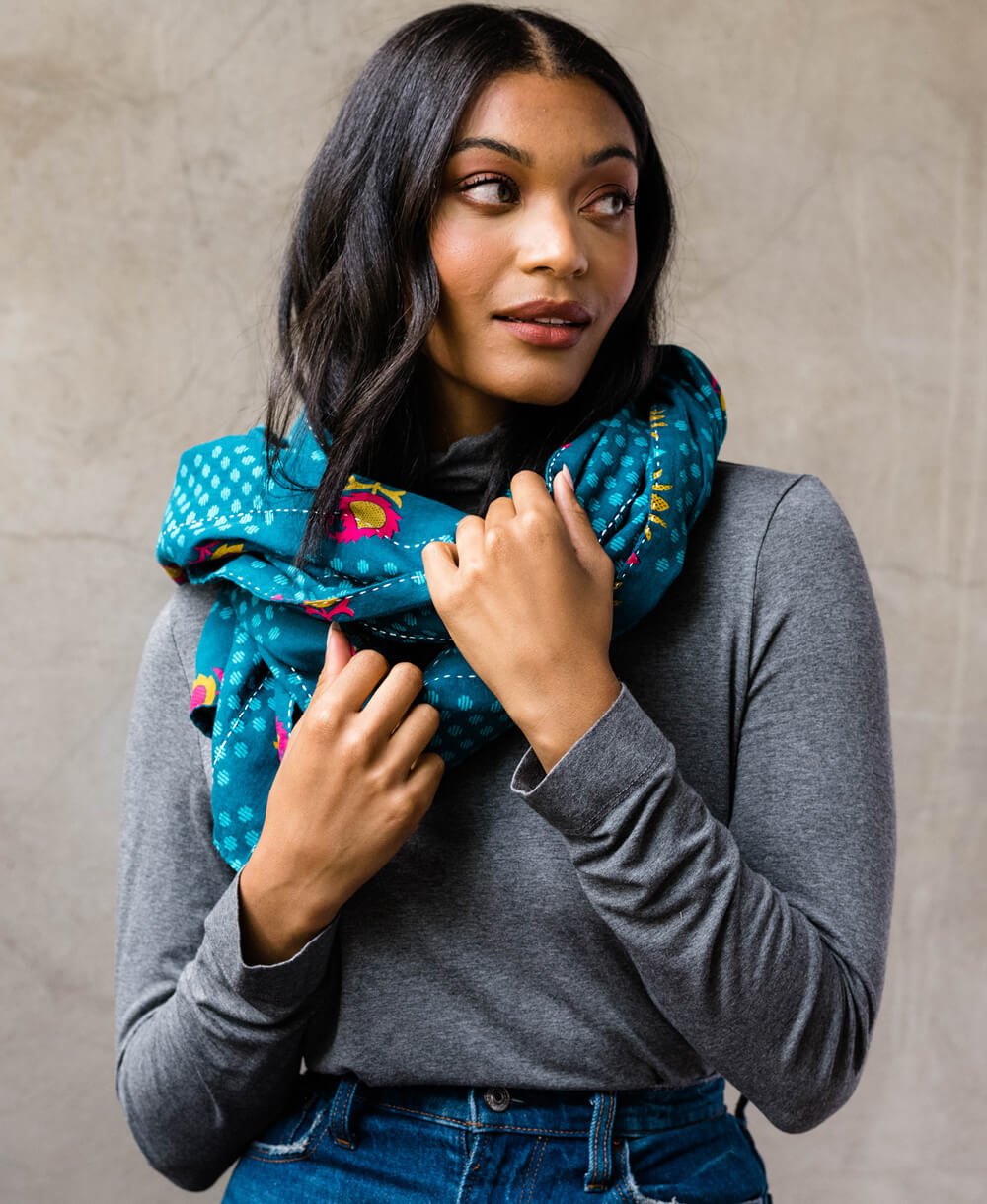 woman wearing teal blue lightweight scarf made and hand embroidered by women artisans