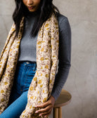 woman wearing long scarf made of vintage cotton fabric featuring a tan and mustard yellow floral print