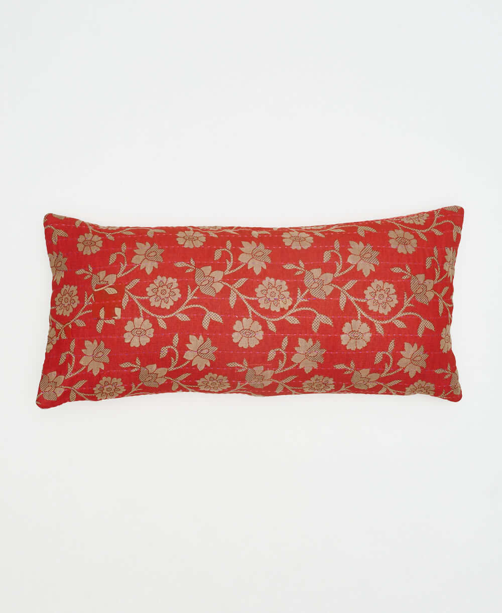 red-orange reversible lumbar pillow with bold tan floral pattern on back