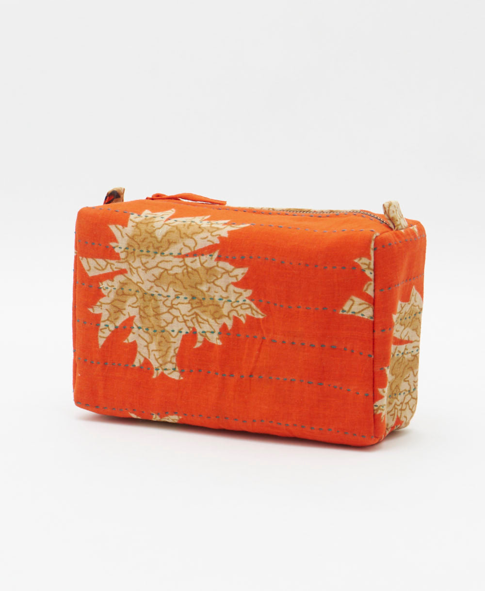 cosmetic travel bag in a tan & orange leaf print with blue hand-stitched kantha embroidery