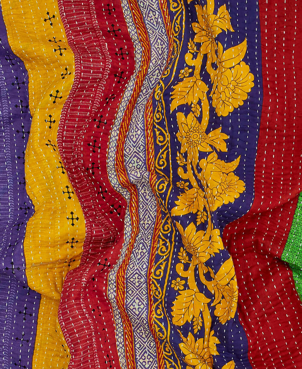 Colorful kantha quilt throw with a tag featuring the hand-stitched signature of the maker