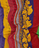 Colorful kantha quilt throw with a tag featuring the hand-stitched signature of the maker