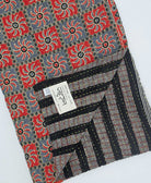 red and grey check print kantha quilt throw with a tag featuring the hand-stitched signature of the maker