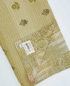 green kantha quilt throw with a tag featuring the hand-stitched signature of the maker