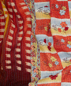 orange botanical kantha quilt throw with a tag featuring the hand-stitched signature of the maker