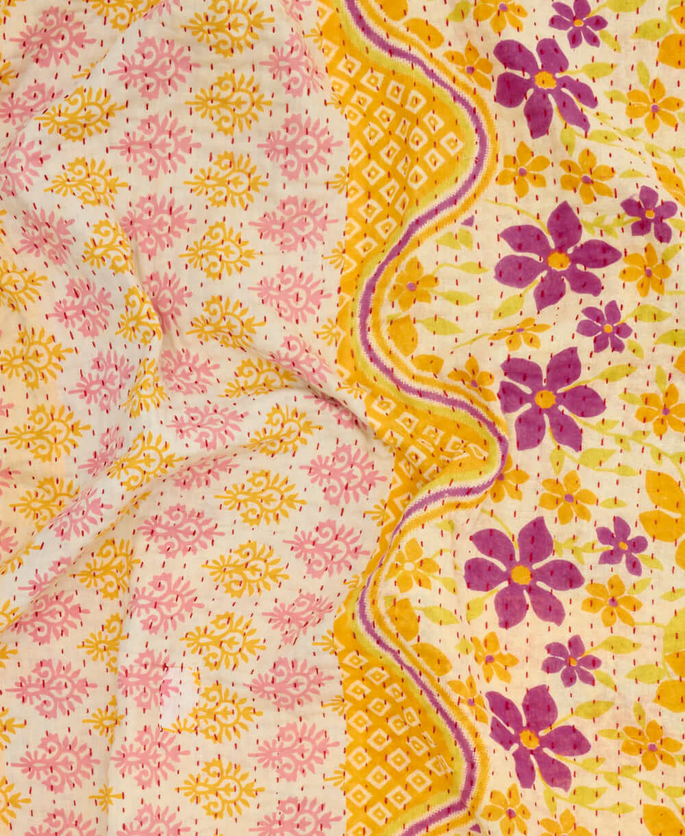 sunny yellow kantha quilt throw with a tag featuring the hand-stitched signature of the maker