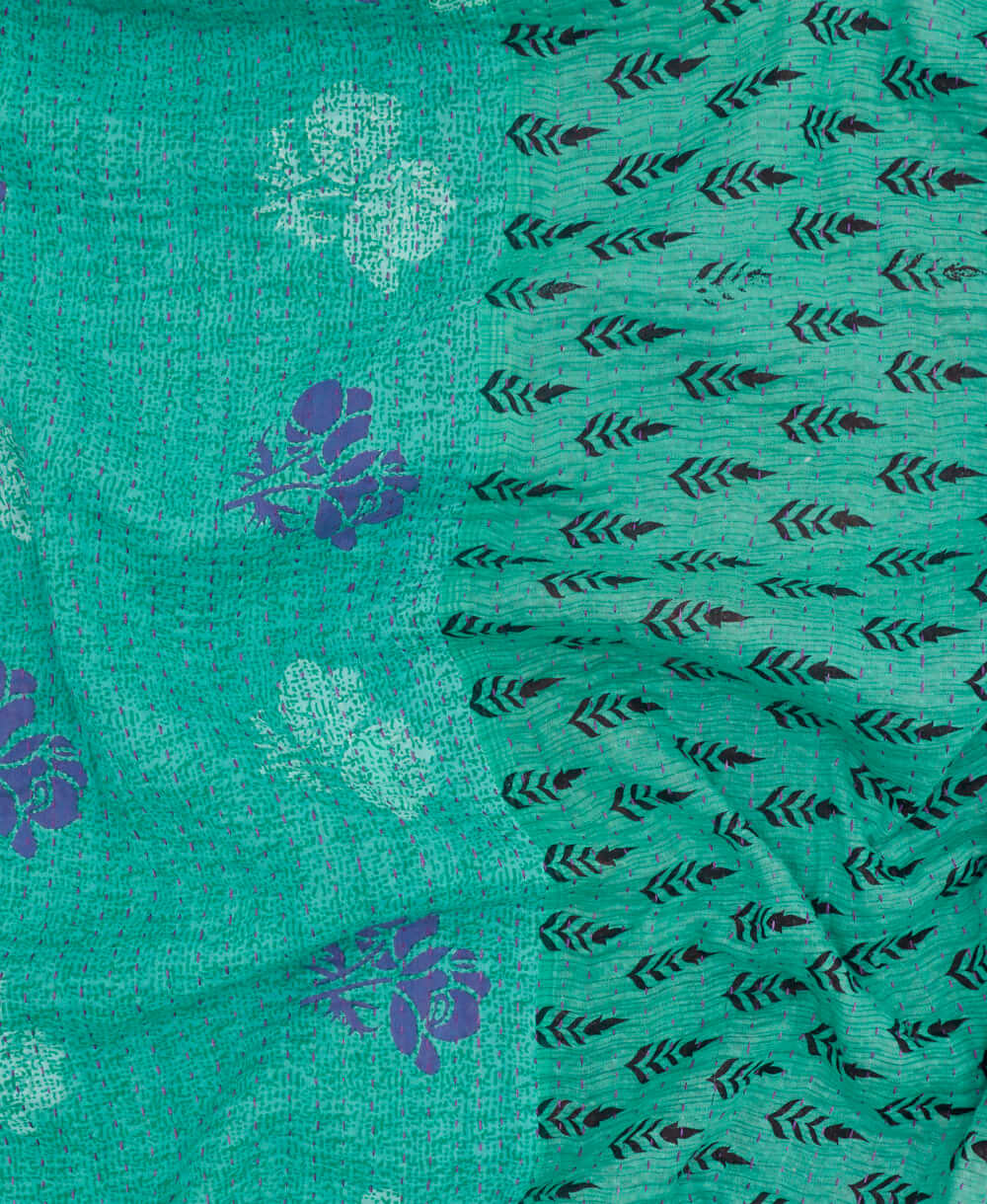 teal stamp kantha quilt throw with a tag featuring the hand-stitched signature of the maker