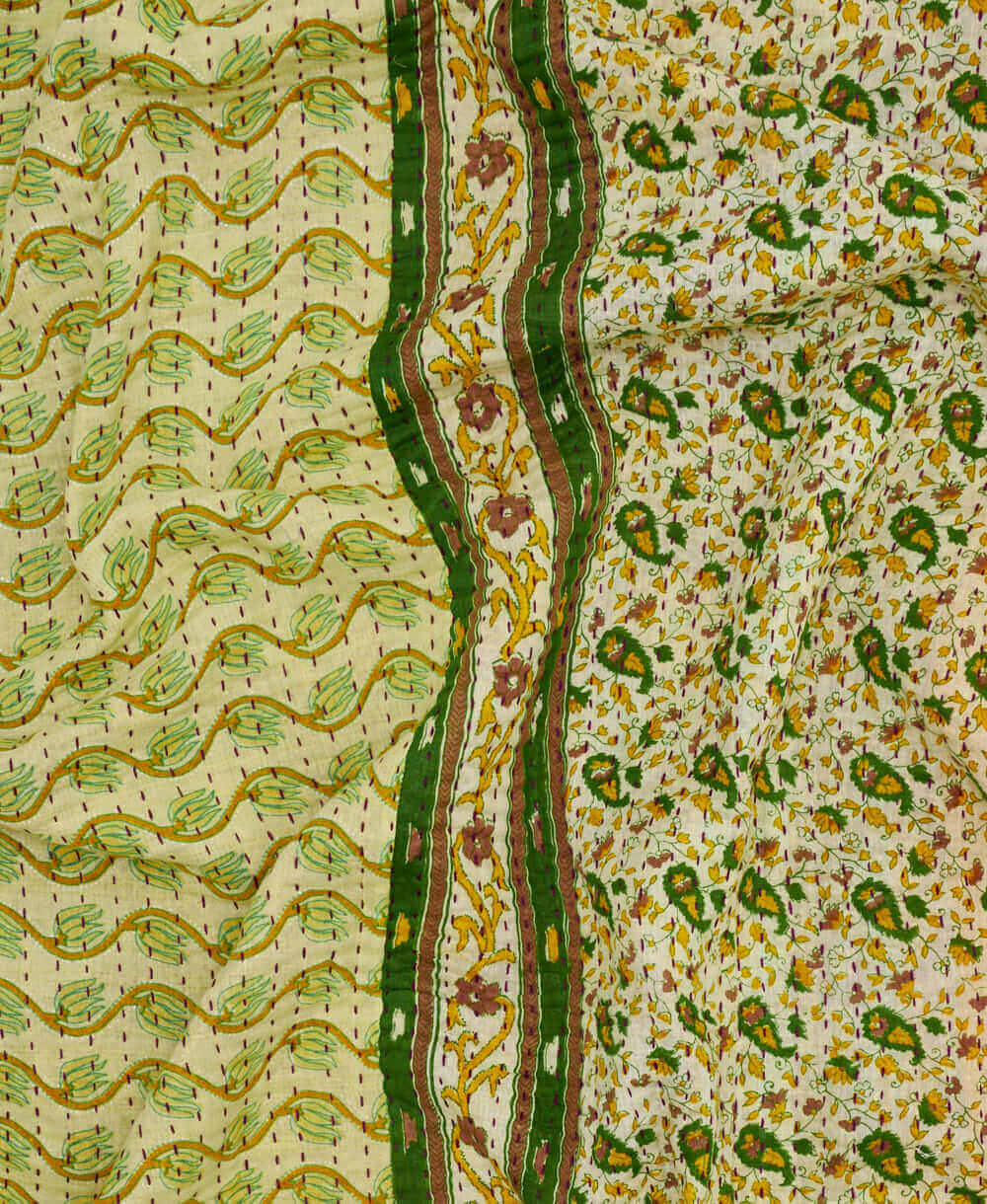 green ornate print kantha quilt throw with a tag featuring the hand-stitched signature of the maker