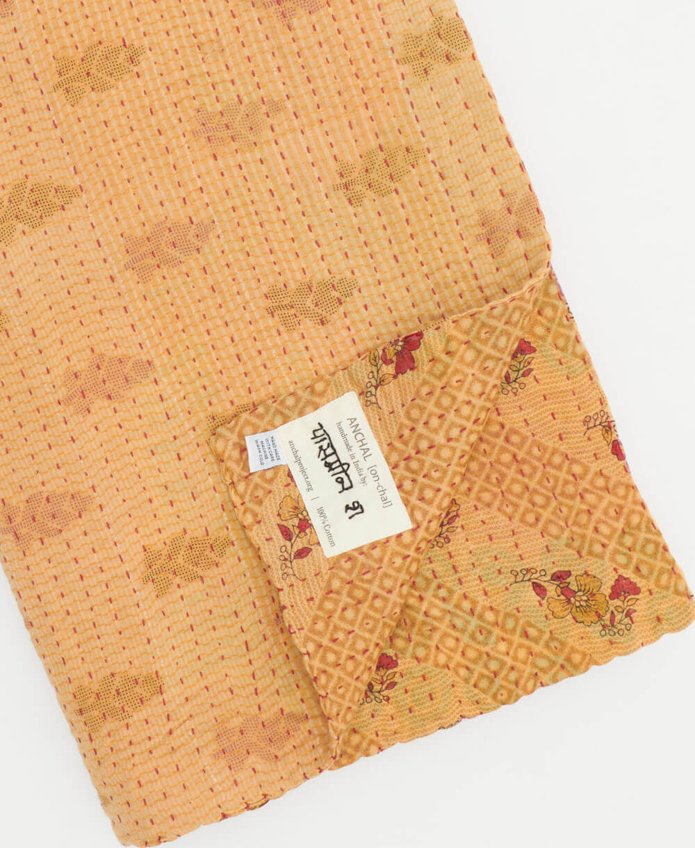 sepia tan & red floral kantha quilt throw with a tag featuring the hand-stitched signature of the maker