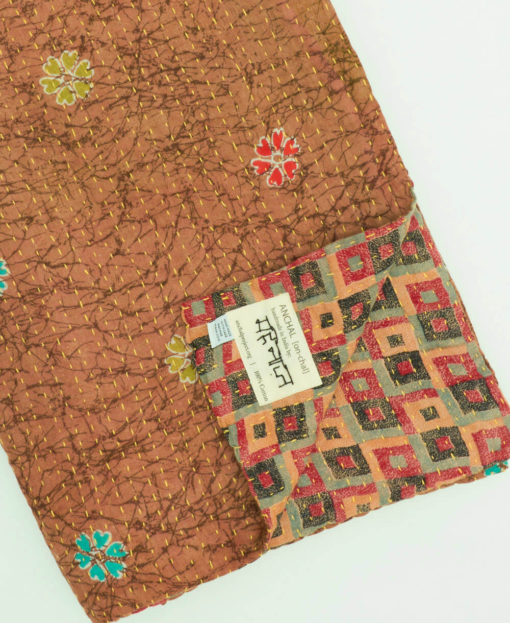 sepia brown checkered kantha quilt throw with a tag featuring the hand-stitched signature of the maker