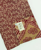 brick red daisy kantha quilt throw with a tag featuring the hand-stitched signature of the maker