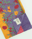 purple, red & orange stripe kantha quilt throw with a tag featuring the hand-stitched signature of the maker