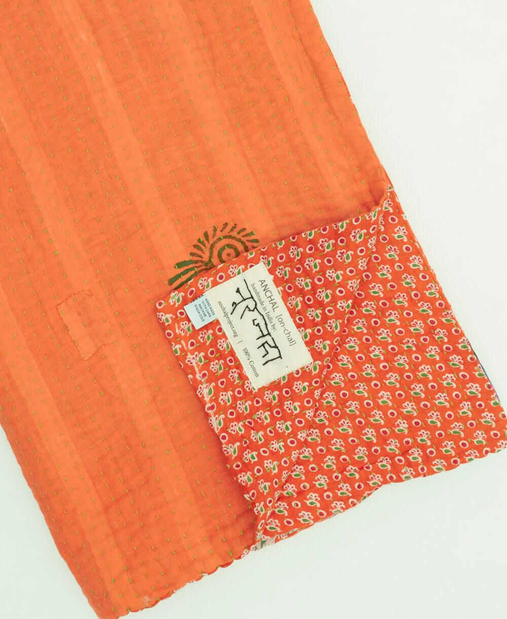 orange & purple tie dye kantha quilt throw with a tag featuring the hand-stitched signature of the maker