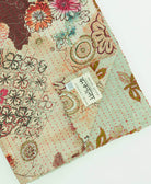 sage green abstract floral kantha quilt throw with a tag featuring the hand-stitched signature of the maker