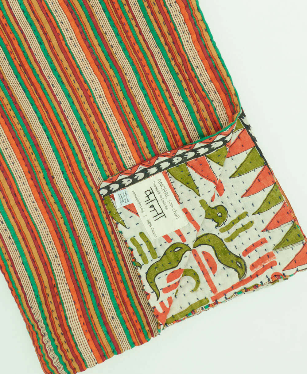 orange, green & yellow stripe kantha quilt throw with a tag featuring the hand-stitched signature of the maker