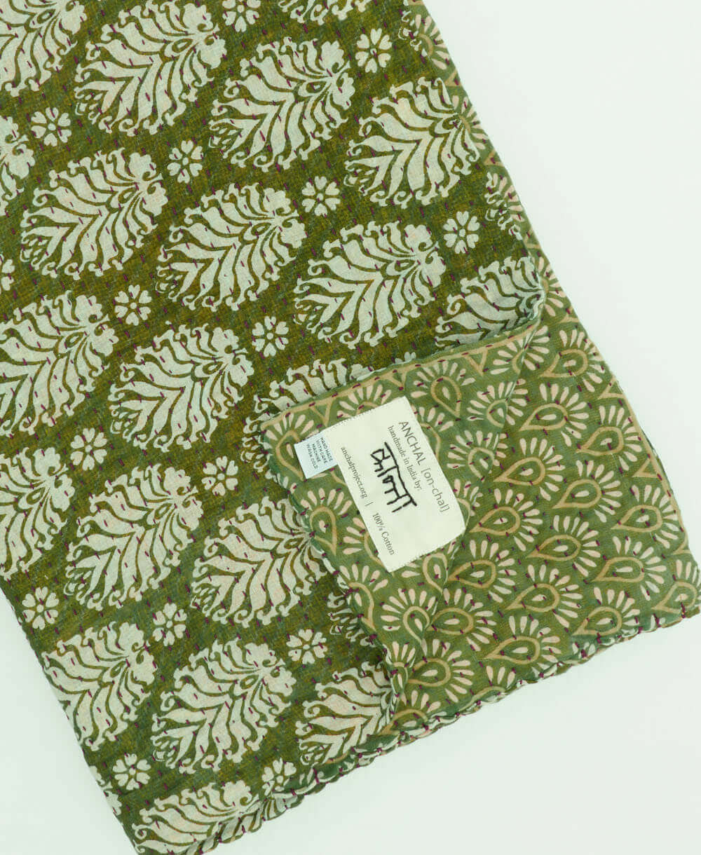 fern green medallion kantha quilt throw with a tag featuring the hand-stitched signature of the maker