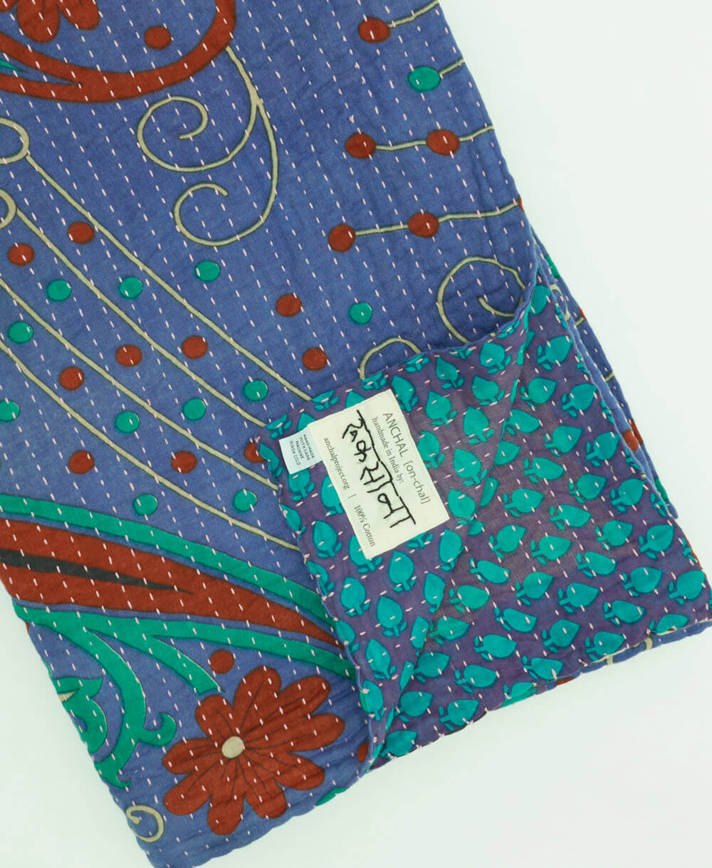 violet blue & red paisley kantha quilt throw with a tag featuring the hand-stitched signature of the maker