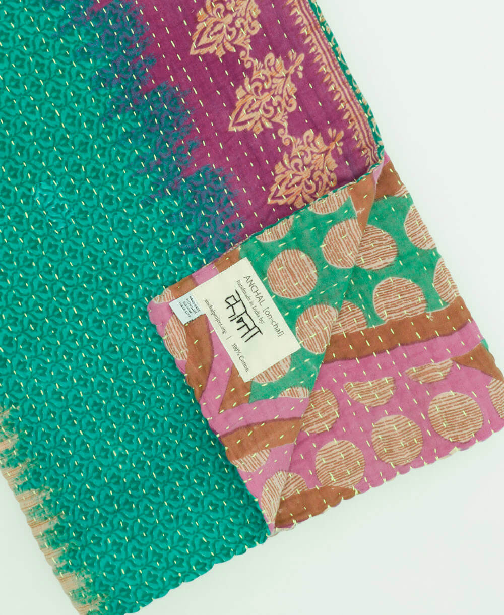 teal & lilac abstract kantha quilt throw with a tag featuring the hand-stitched signature of the maker